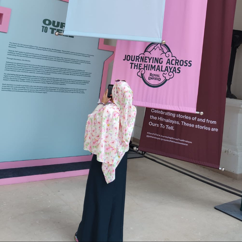 Person standing in front of a display with 'Tell' and 'Journeying Across the Himalayas' banners.
